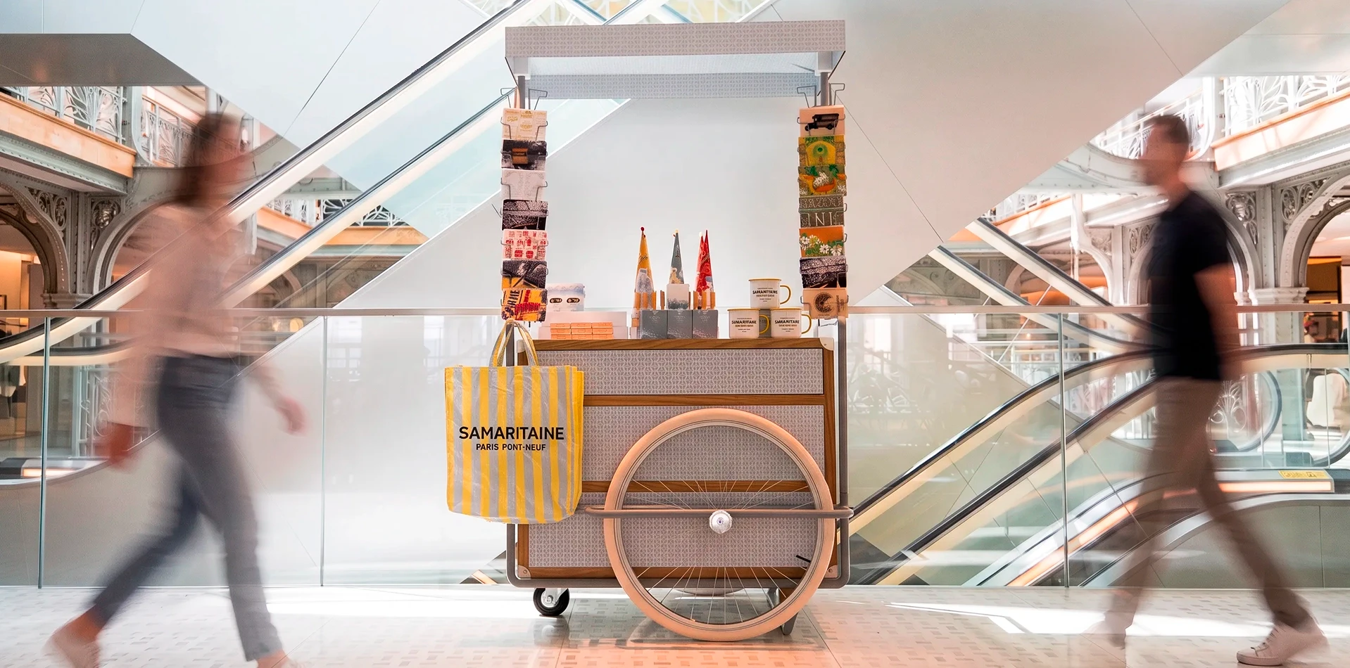 Samaritaine, chariot de produits de la marque au pied des escaliers mécaniques